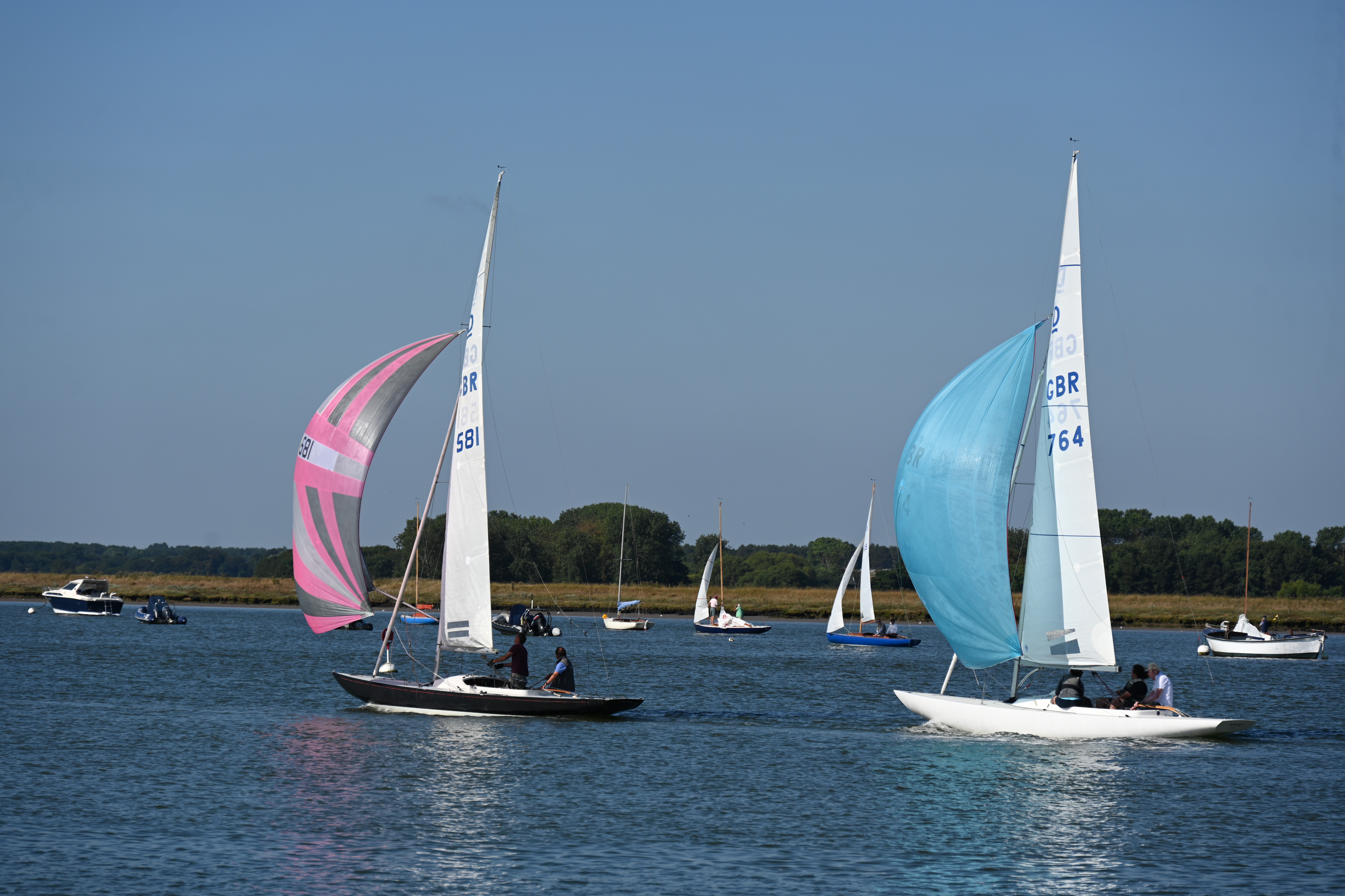 dragon keelboats with pink and blue spinnakers on the water in Aldeburgh
